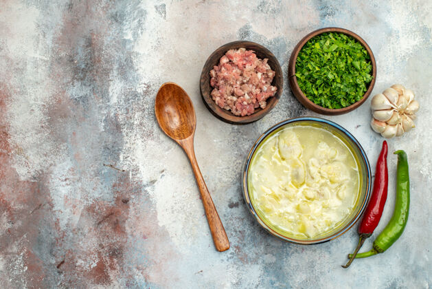 胡椒俯瞰杜什巴拉饺子汤碗大蒜辣椒木勺碗肉和绿色裸体表面与复制空间碗勺子顶部