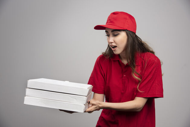 食物女信使紧握着灰色墙上的比萨饼盒服务表情年轻人