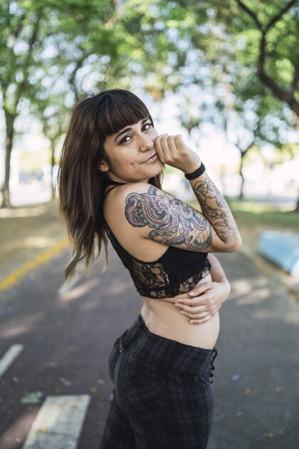 纹身年轻迷人的白种女人站在公园里纹身 做一张可爱的脸魅力美丽女性
