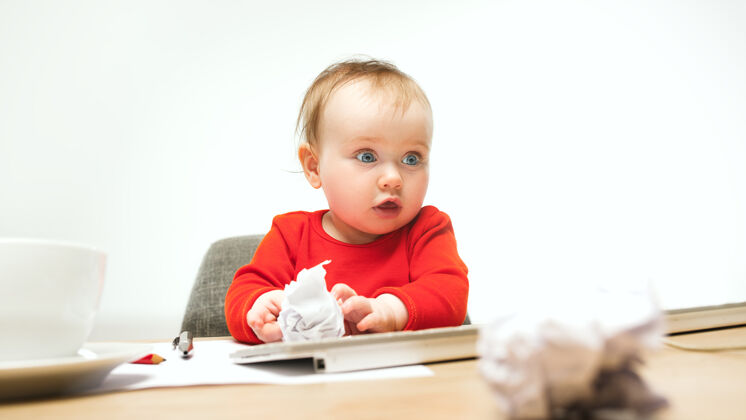 电脑快乐的小女婴坐在白色的现代电脑或笔记本电脑的键盘上坐现代婴儿