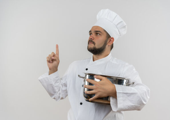 厨师年轻的男厨师穿着厨师制服拿着锅子看着旁边竖起的手指隔离在空白处手指侧拿着