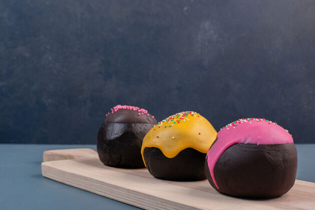 黄色三个甜甜圈在木板上新鲜巧克力色粉色