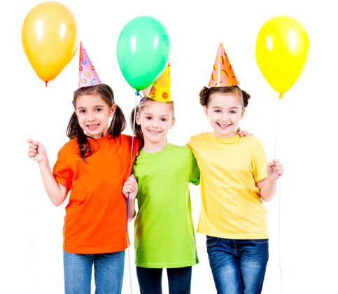 庆祝三个可爱的小女孩的肖像 带着彩色气球和派对帽-隔离在一个白色的椅子上帽子欢快有色