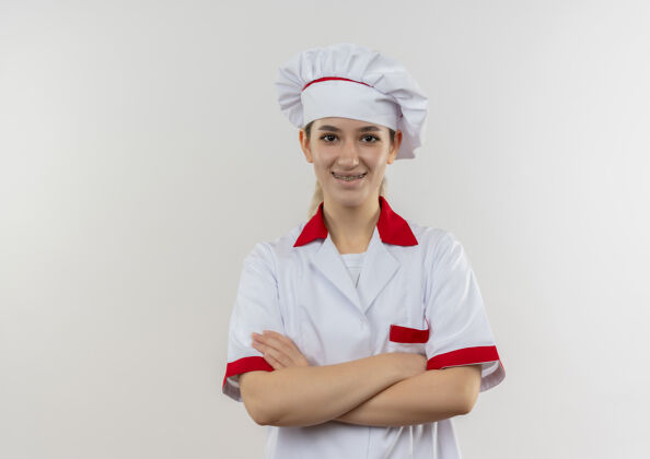 牙科面带微笑的年轻漂亮厨师身着厨师制服 戴着牙套 以封闭的姿势站在空白处复制微笑漂亮