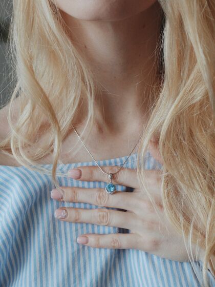 金属特写镜头中的一位女性穿着蓝色衬衫 戴着一条漂亮的项链和一个漂亮的吊坠奢侈品珠宝十字架