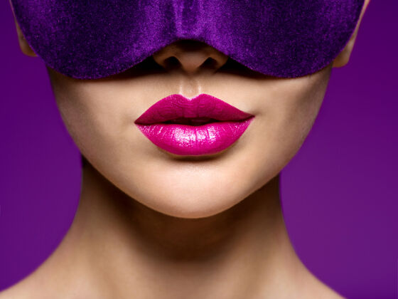 宏观一个脸上戴着紫色戏剧面具 嘴唇是紫色的女人的肖像年轻紫色女性
