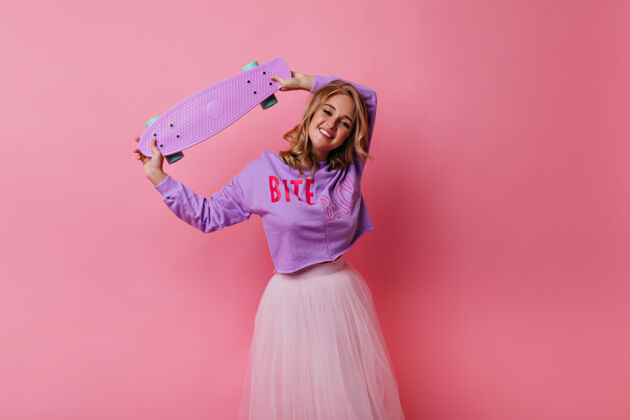 模特温文尔雅的年轻女士穿着华丽的裙子优雅的金发女孩拿着粉红色的滑板滑板成人休闲