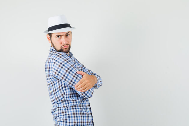 发型年轻人交叉着双臂站在格子衬衫里 戴着帽子 表情严肃商人成功衬衫