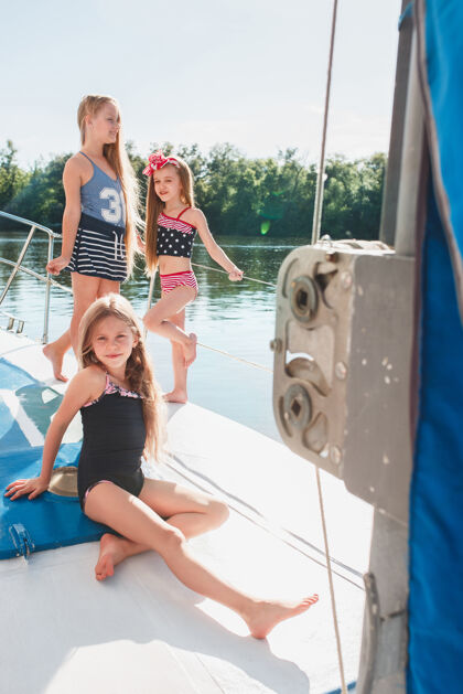 欢乐孩子们在海上游艇上青少年或女童在户外蓝天下巡航姐妹水