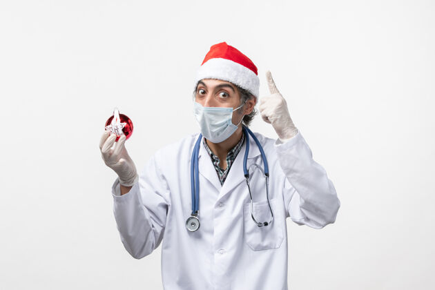 实验室外套正面图白墙上戴着玩具面具的男医生健康酷似节日病毒病毒圣诞节护士