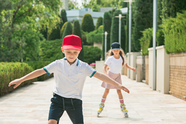 活跃在公园里 一对迷人的年轻夫妇穿着溜冰鞋一起滑冰年轻的白人男孩和女孩锻炼健身户外