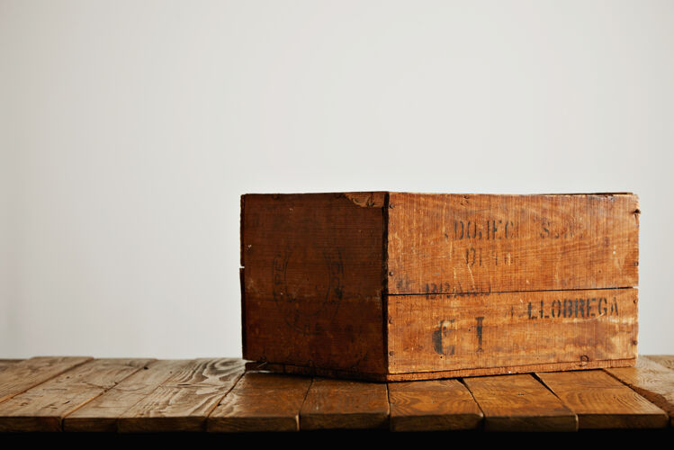 箱子棕色乡村木酒盒 白色墙壁背景下的木桌上几乎看不清黑色字母箱子木制的顶部