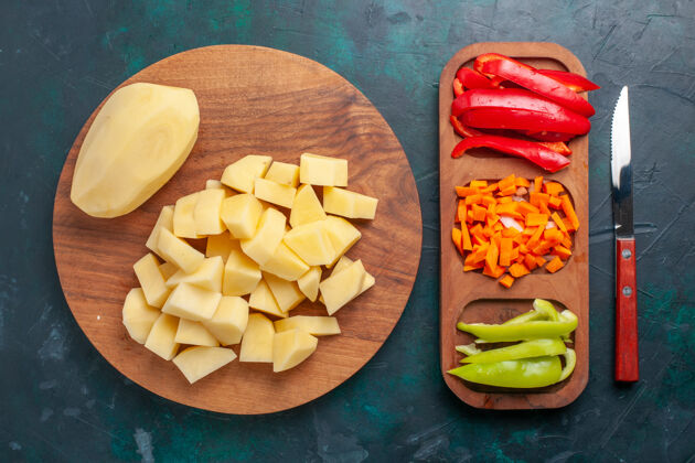 食用水果俯视图：深蓝色背景上切好的新鲜土豆和剥下来的蔬菜甜瓜背景去皮