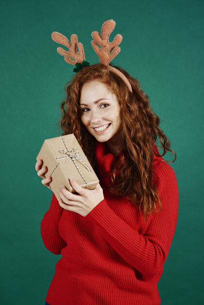 时装模特在摄影棚拍摄的手持圣诞礼物的快乐女孩的肖像牙齿圣诞节女人