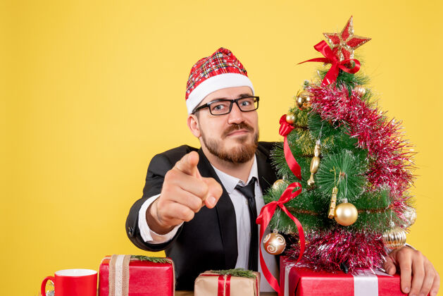 礼物正面图男性工人坐在他工作的地方后面 黄色的礼物花束新郎圣诞节