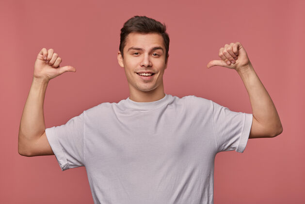 有趣年轻开朗帅哥的画像穿着一件空白的t恤 指着自己 站在粉红色的椅子上 面带微笑积极酷男性