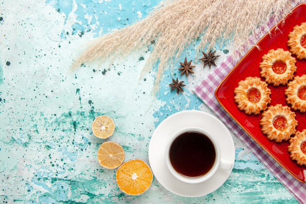 糖顶视图糖饼干在红色盘子里 蓝色背景上有一杯茶饮料热的早餐