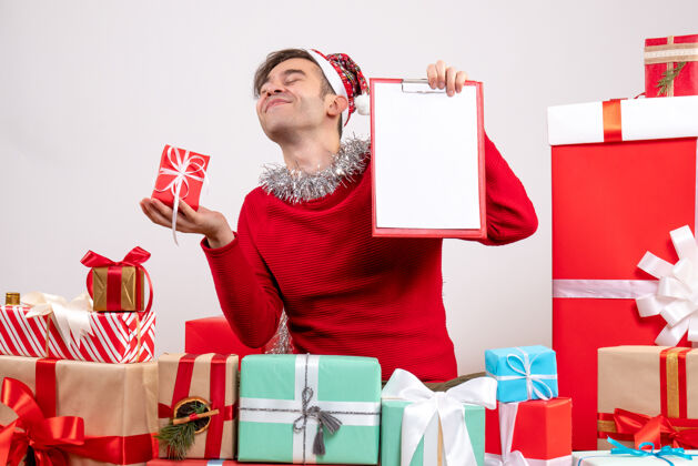购物前视图满意的年轻人拿着礼物和剪贴板围坐在圣诞节礼物礼物剪贴板包