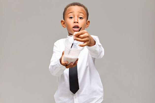 领带健康的生活方式 食物 饮料和童年的概念图片中情绪激动的非洲裔美国学生穿着制服拿着塑料罐与水果奶昔 提供给你一些男孩年轻光