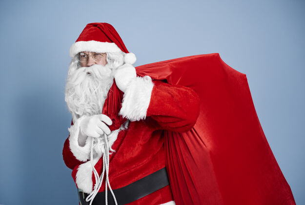 抱疲惫的圣诞老人背着沉重的麻袋站着圣诞老人背