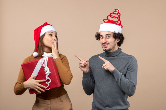 头盔新年气氛喜庆的概念与有趣可爱的夫妇穿着灰色的红色圣诞老人帽子肖像帽子男人