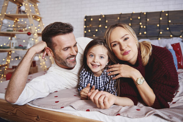 装饰圣诞快乐的一家人在床上的画像放松躺下圣诞灯