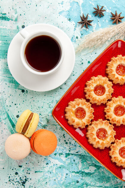 早餐在蓝色背景上俯瞰一杯茶和麦卡龙糖饼干饼干背景派