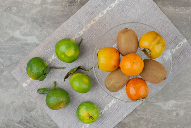 成熟桌布上放着新鲜的橘子 猕猴桃和柿子水果猕猴桃视图