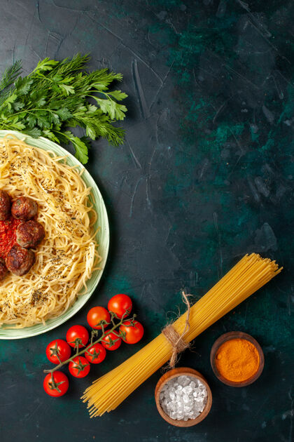 美味在深蓝色的桌子上俯瞰美味的意大利通心粉和肉丸子和蔬菜意大利午餐肉丸