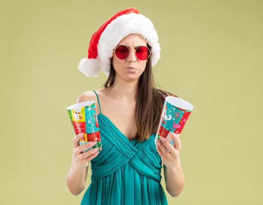 圣诞老人一个戴着太阳眼镜 戴着圣诞帽 拿着纸杯看东西的白人女孩眼镜纸杯子
