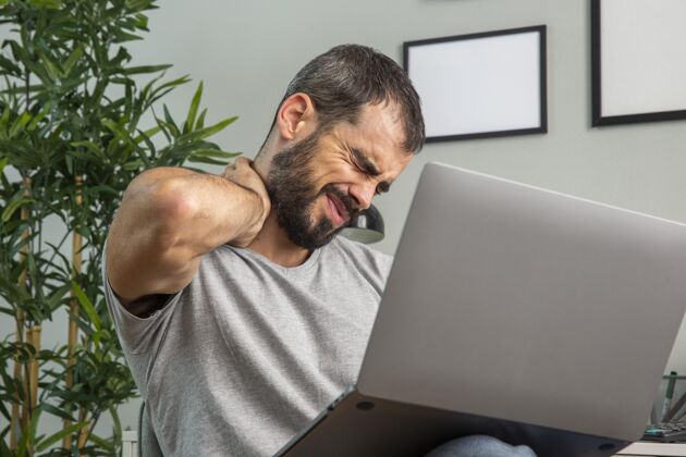 男人男人在家里用笔记本电脑工作时颈部疼痛职业家庭工作