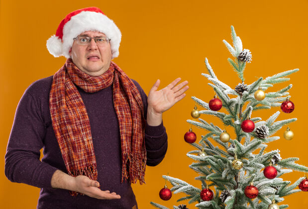 站着戴着眼镜 戴着圣诞帽 脖子上围着围巾的恼怒的成年人圣诞树帽子眼镜