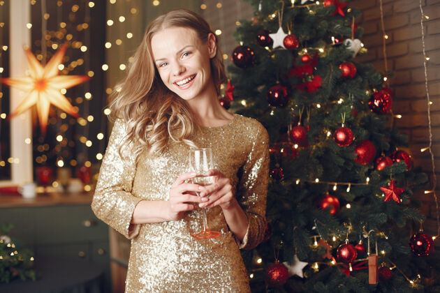 时尚优雅的女士在圣诞树旁女士在家拿香槟奢华新年前夜人