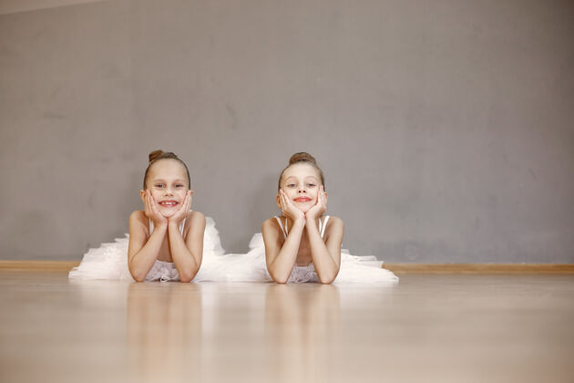 班级穿着白色芭蕾舞服的可爱的小芭蕾舞演员穿着尖头鞋的孩子们在房间里跳舞舞蹈课上的孩子们古典女孩运动