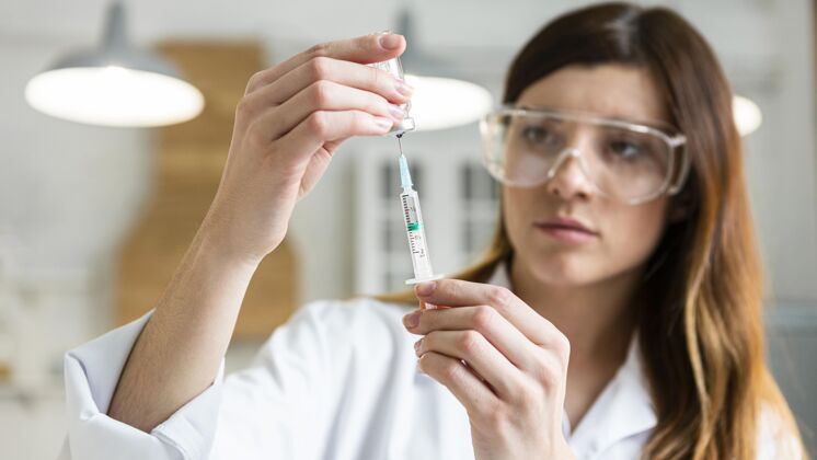 实验戴着安全眼镜拿着装有疫苗的注射器的女科学家调查水平女性