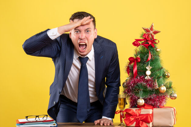 职业在圣诞树旁 一个男人把手放在她的额头上 把礼物放在黄色的椅子上男男人办公室