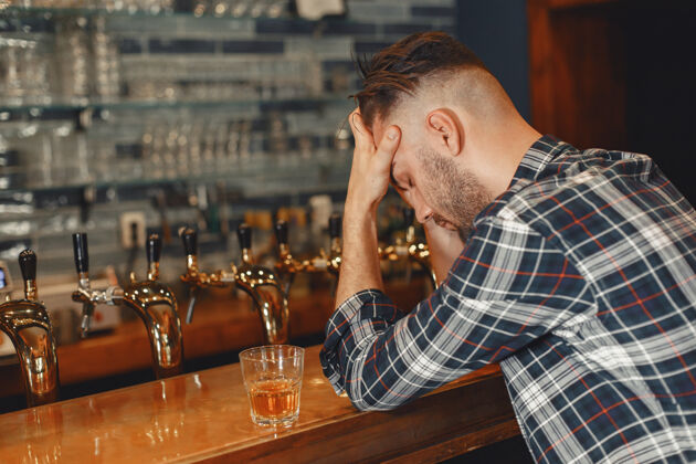 西装一个穿衬衫的男人手里拿着一个玻璃杯那个家伙正坐在酒吧里 抱着他的头酒吧头发成人