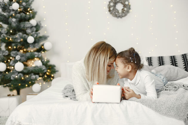 女儿人们在为圣诞节做准备母亲在和女儿玩耍一家人在节日的房间里休息孩子穿着毛衣孩子光泽毛衣
