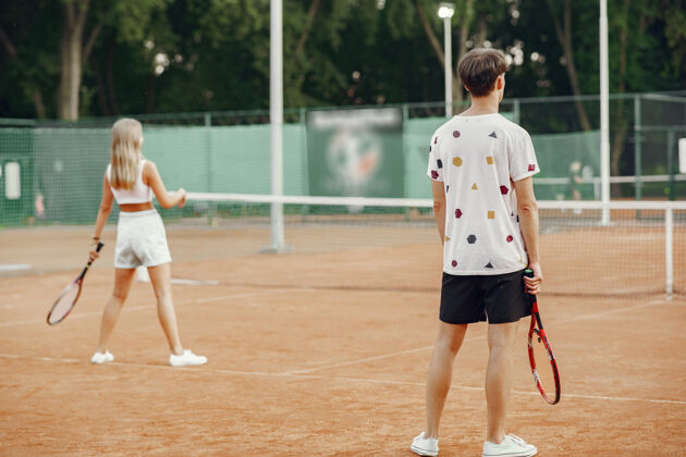 一起网球场上的一对年轻夫妇两个穿着运动服的网球运动员活跃女孩运动装