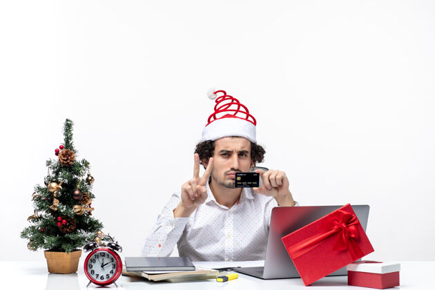 商务戴着圣诞老人帽子 拿着银行卡的商人在办公室里惊讶地看着卡片圣诞老人人