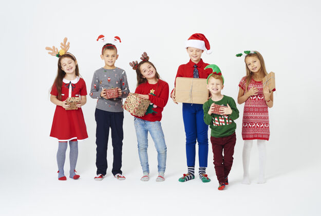 站立带着圣诞礼物的快乐的孩子们礼品盒展示人