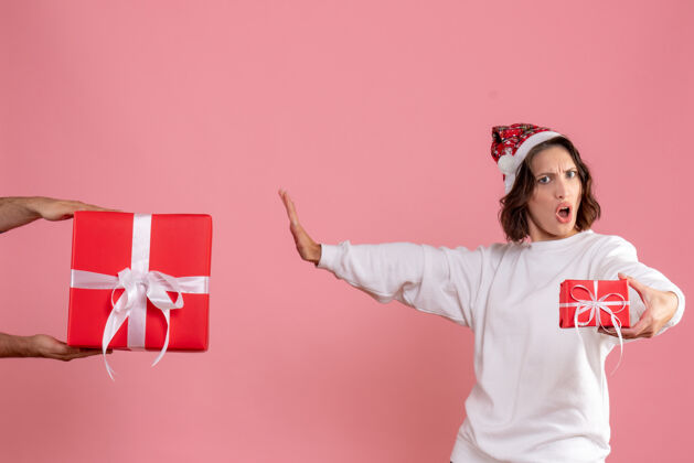 女性年轻女子拿着小礼物 不接受粉红色墙上男人的礼物情感圣诞节礼物