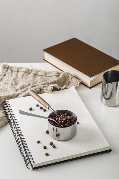 布料高角度的咖啡豆杯在笔记本上高角饮料