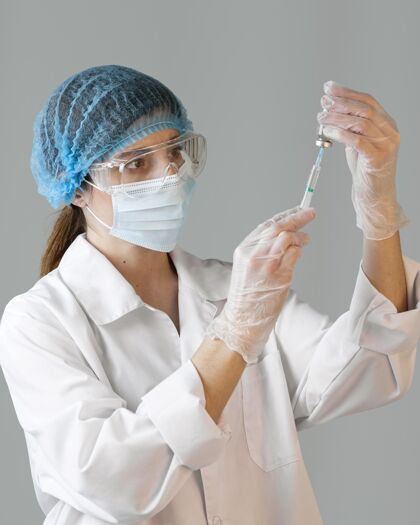 研究员戴着安全眼镜和医用面罩拿着注射器的女科学家科学网络头发