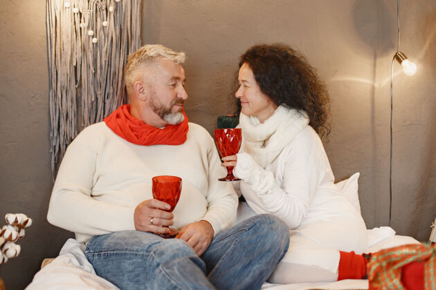 玻璃年龄和人的概念家里的老年夫妇穿着白色针织毛衣的女人妻子在一起感情