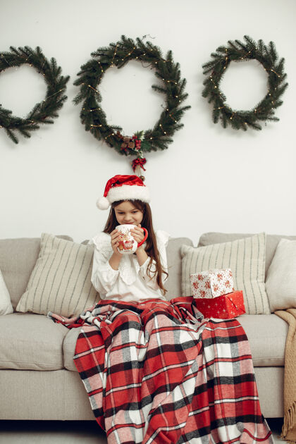 女性穿白色毛衣的孩子坐在圣诞树旁的女儿传统睡衣女儿
