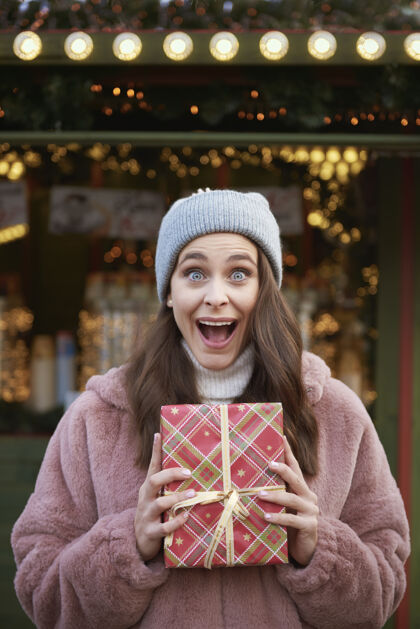 消费主义圣诞节市场上一个惊喜的女人拿着圣诞礼物庆祝特写集市