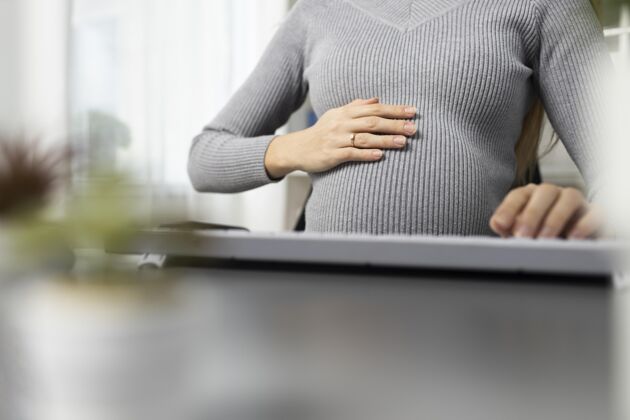 职业坐在办公桌旁抱着肚子的孕妇职业工作电脑