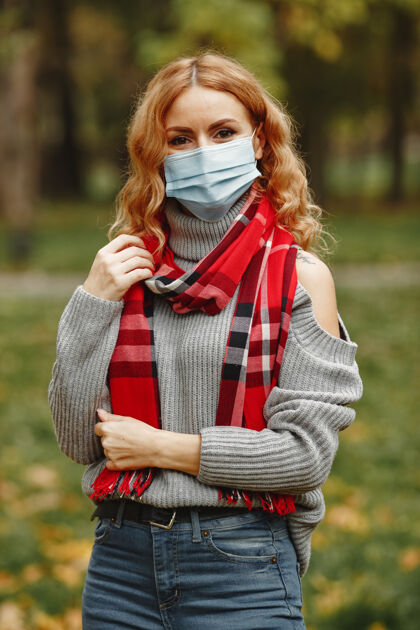 人秋天森林里的女人戴面具的人冠状病毒主题戴红领巾的女人秋天面具流行病