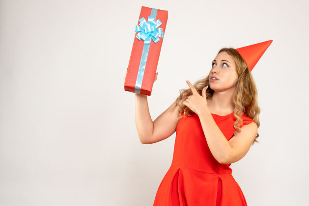 礼物正面图身着红色连衣裙的年轻女性用礼物庆祝圣诞节微笑女性年轻女性